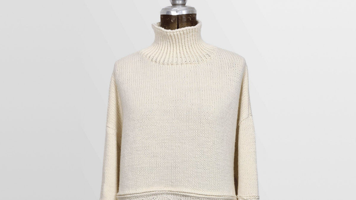 Gansey-Pullover Coconut Milk aus Merinowolle in Natur mit Rollkragen auf einer Schneiderbüste