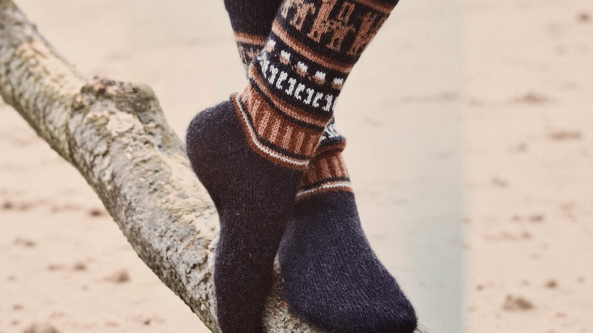 Dunkle Mustersocken mit sichtbaren Fersen und Fußspitzen auf einem Ast. Originalfoto mit seitlich durch KI erweitertem Hintergrund.