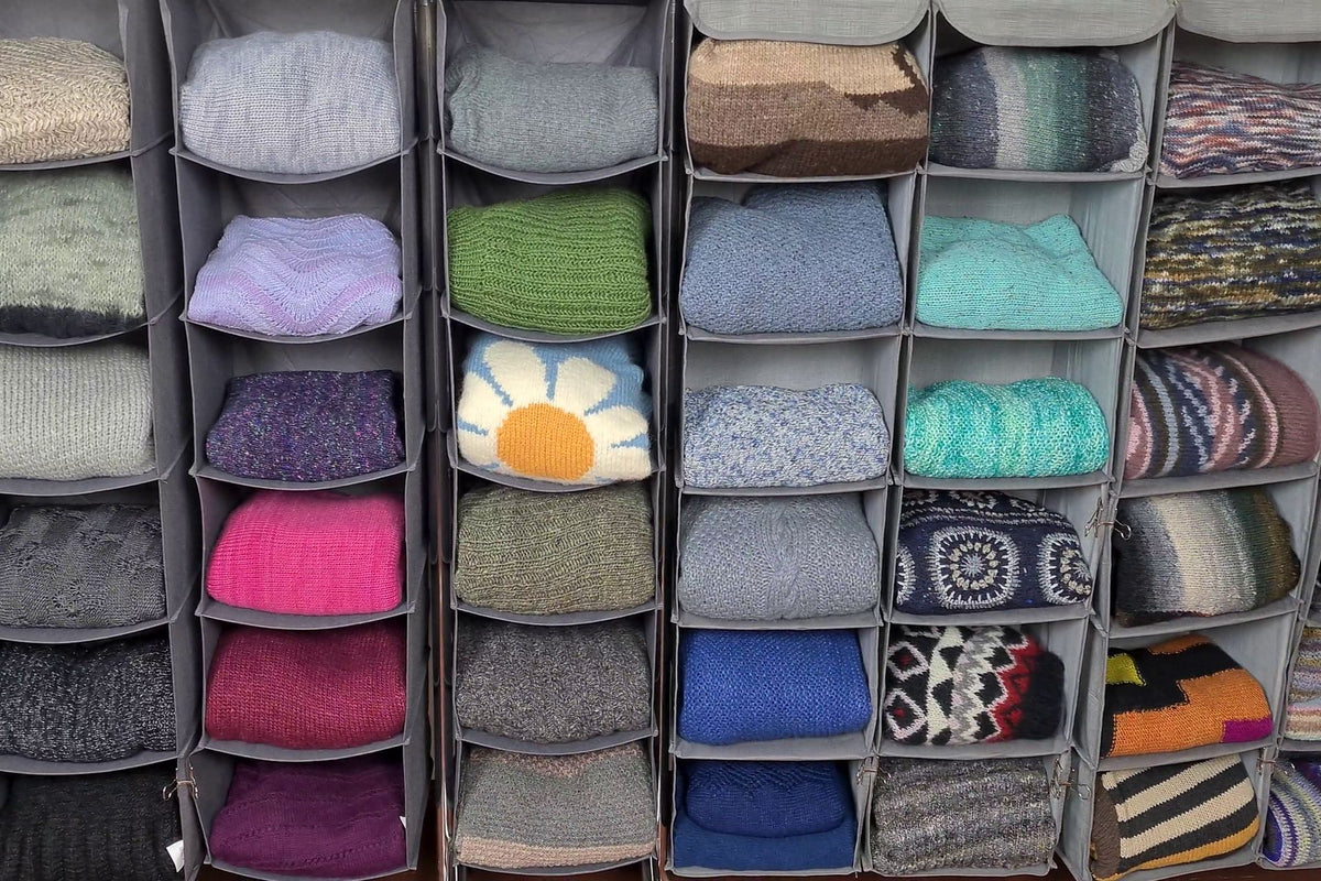 Gefaltete Strickpullover liegen einzeln in offenen Stoffregalen