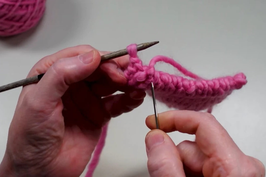Wollnadel beim italienischen Abketten an einem pinkfarbenen 1x1-Rippenbündchen