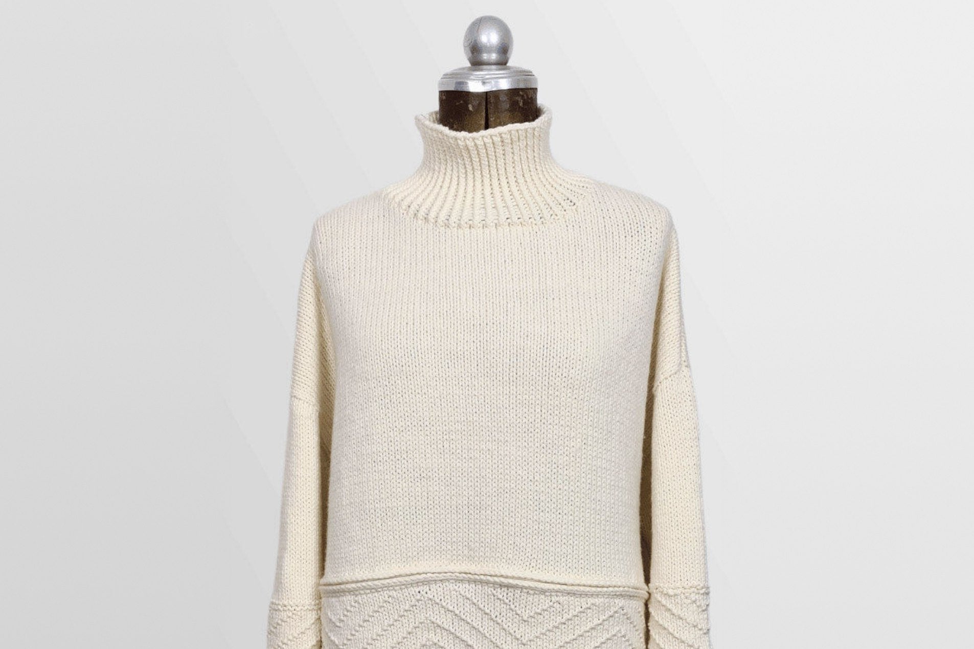 Gansey-Pullover Coconut Milk aus Merinowolle in Natur mit Rollkragen auf einer Schneiderbüste