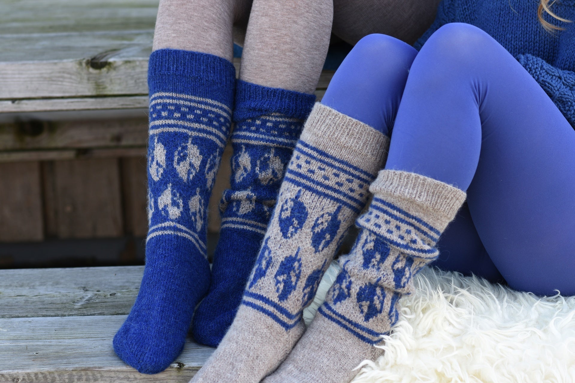 Zwei getragene Sockenpaare in Blau und Beige mit geometrischem Muster auf einer Holzbank.