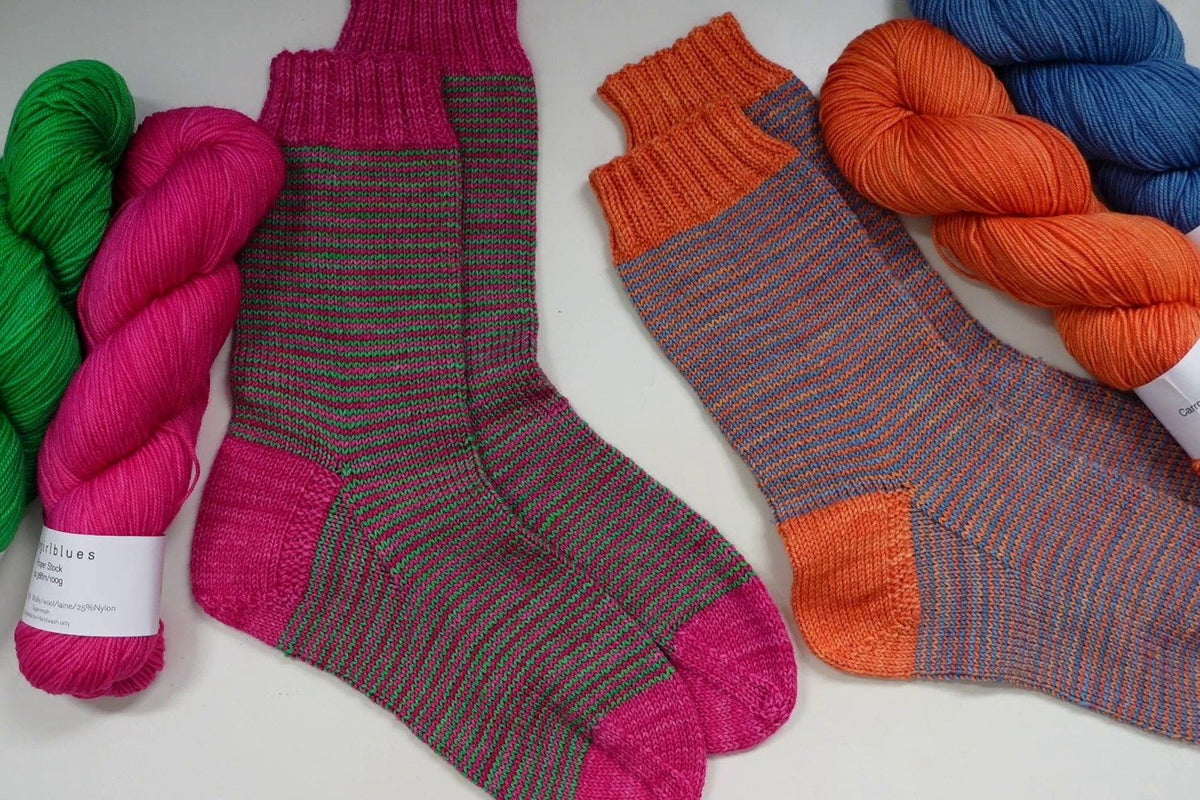 Ringelsocken in zwei Farbkombinationen neben den Garnsträngen