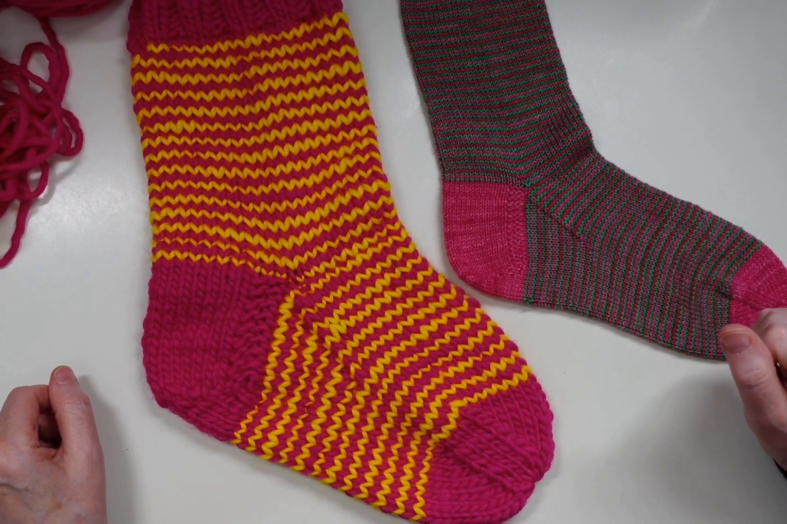 Fertige Ringelsocke mit pinker Bandspitze neben einer zweiten Socke