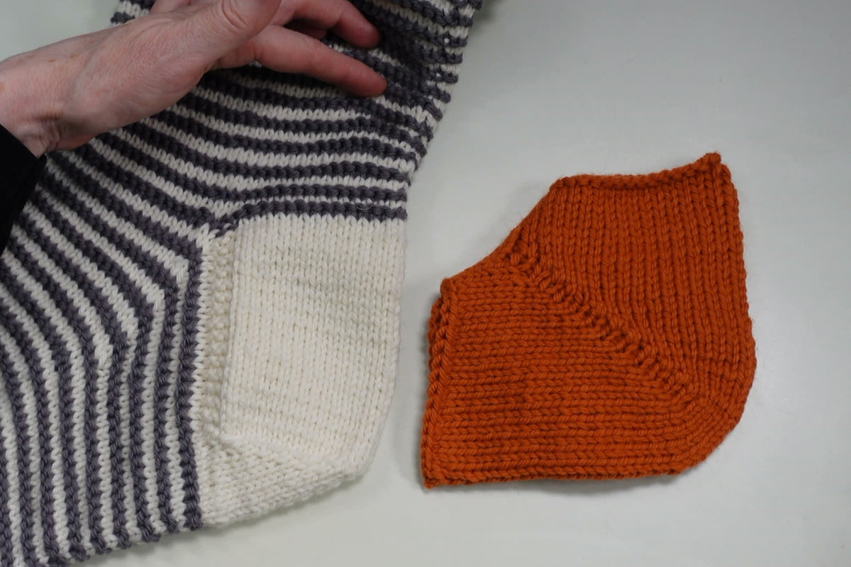 Weiße Herzchenferse mit Fersenwand an einer geringelten Socke neben einer orangen Bumerangferse