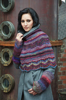 Poncho und Pulswärmer Iced Blackberry aus buntem Verlaufsgarn mit gestrickter Bortenkante.